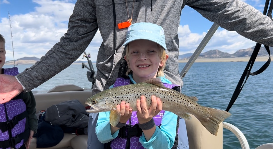 A young angler holding a brown trout
